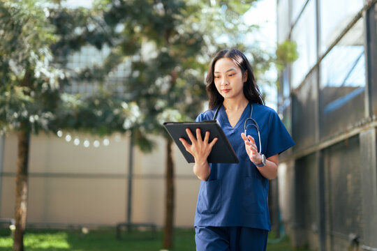 Asian medical professional managing digital health records outdoors