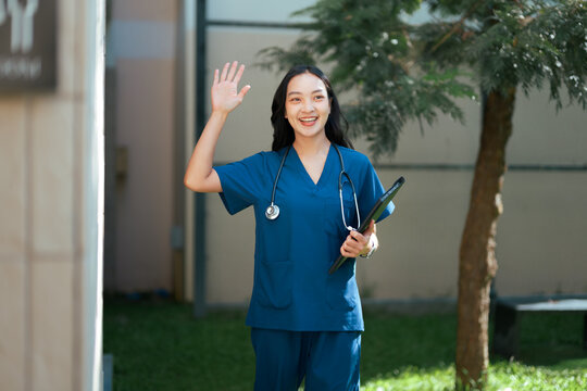Asian nurse waving hand with friendly gesture