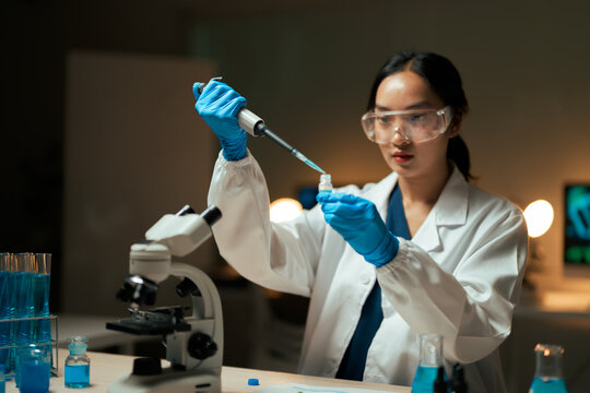 Female scientist pipetting liquid into vial in laboratory