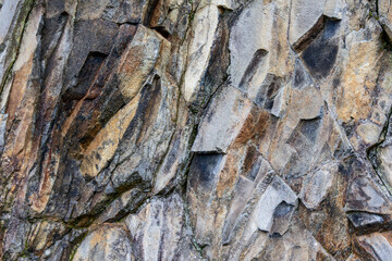Stone texture with fractured geometric shapes, shades of gray and brown intersect across the rough mineral surface forming a natural abstract background