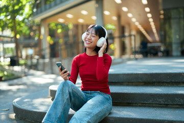 Young woman enjoying music listening headphones outdoors