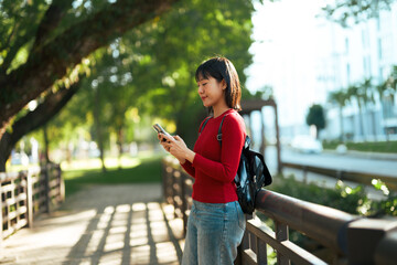 Young woman using smartphone on park bridge