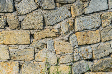 Close-up of an ancient, weathered stone wall in a Central European village, built with irregularly shaped stones and showing signs of time cracks, varying colors due to exposure Natural lighting e