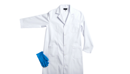 Plain white lab coat with a blue glove casually placed below, isolated on a solid black background
