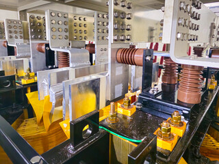 A black box with a yellow cover. The box is made of metal. There are wires and bolts on the box