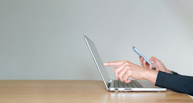 Businesswoman using laptop and smartphone, remote work concept. Modern office desk with technology for online work, productivity and communication in professional digital workplace. - Powered by Adobe