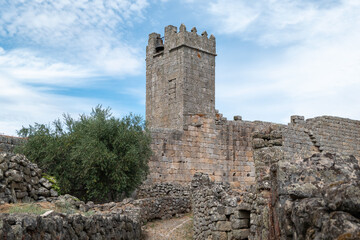 Vista Panor&acirc;mica da aldeia desabitada de Marialva com caminhos a ladear muros de granito em ru&iacute;nas, com uma das  torres do castelo sob um c&eacute;u parcialmente nublado em Portugal