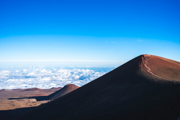 Volcanic cinder cones and mountain road along the lower slopes of Mauna Kea under moving clouds, Hawaii Island, USA