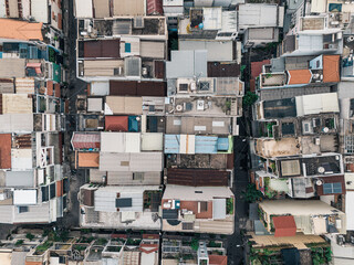 A city view of a neighborhood with many houses. The houses are all different sizes and colors. There are some green plants in the area