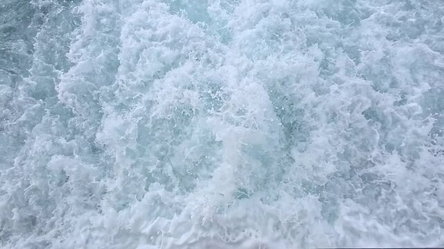 Slow motion close-up of turbulent white foaming water with churning waves and bubbles, abstract texture background of boat wake or sea surf