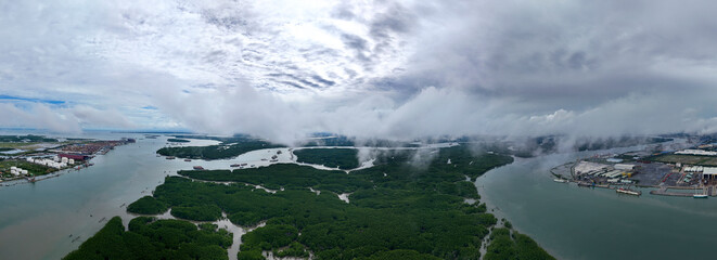 A view of a river with a cloudy sky in the background. The river is surrounded by trees and there are boats in the water
