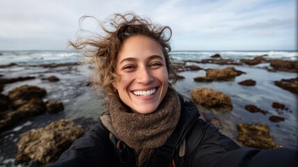 Smiling woman posing by rocky shoreline in coastal setting.