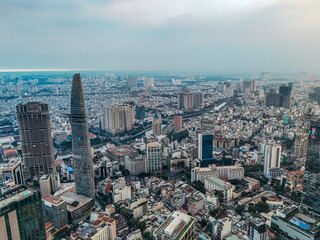 A city with tall buildings and a large hill. The hill is covered in trees. The city is in the middle of a large valley