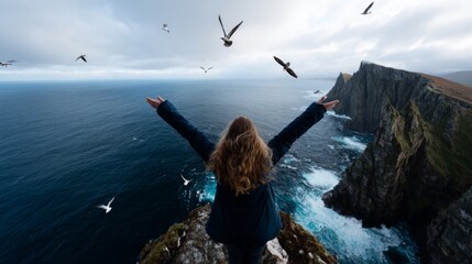 Woman standing on cliff overlooking ocean, arms raised in joy, birds flying around her.