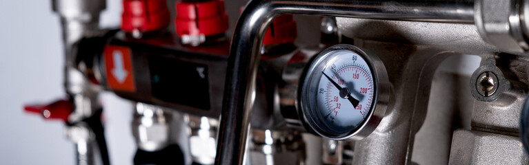 Complex residential heating manifold system with valves, gauges, and piping network. banner