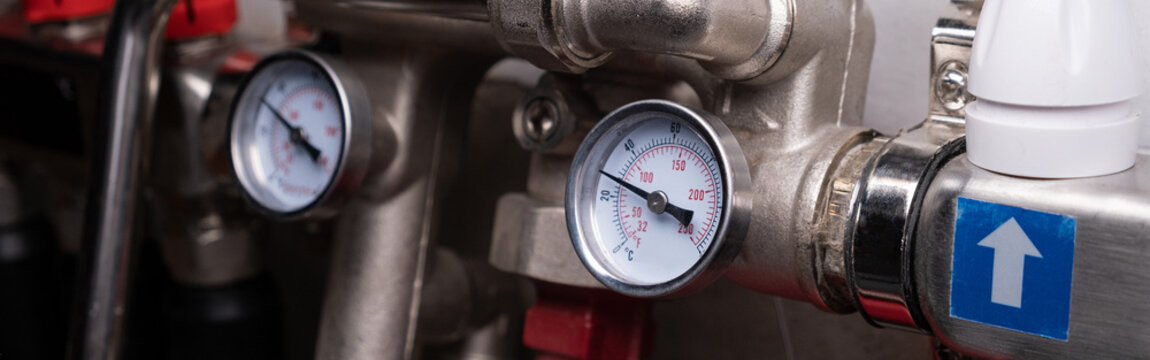 Complex residential heating manifold system with valves, gauges, and piping network. banner
