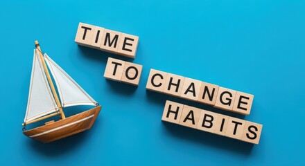 Wooden blocks spelling 'Time to Change Habits' with a sailboat model encourages a personal development journey and positive lifestyle choices on a vibrant blue background