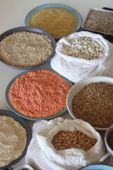Bowls and bags full of various healthy grains and legumes. Selective focus.