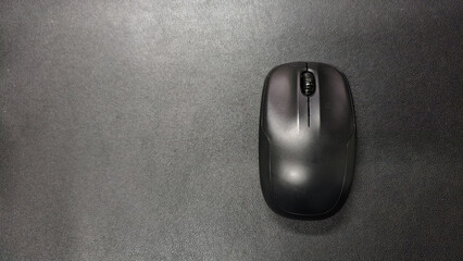 a black mouse on the black leather surface bacground