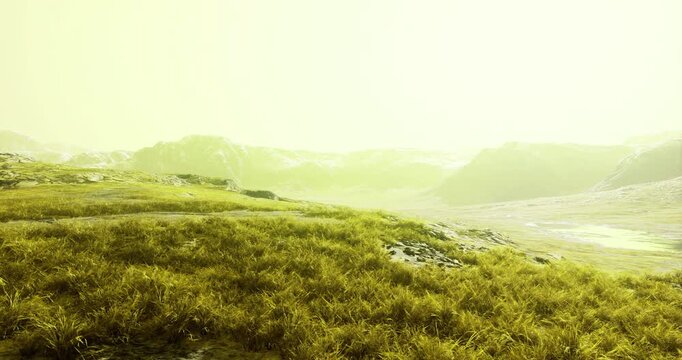 Lush green terrain stretches across the foreground, surrounded by rugged mountains under an ethereal yellow glow during daytime. Nature exhibits vivid colors and serene beauty.