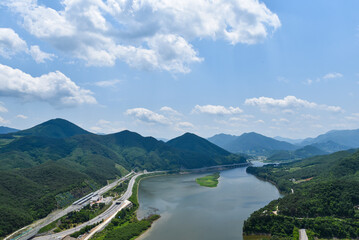 A river runs through a valley with mountains in the background. The sky is clear and blue. There are no clouds in the sky