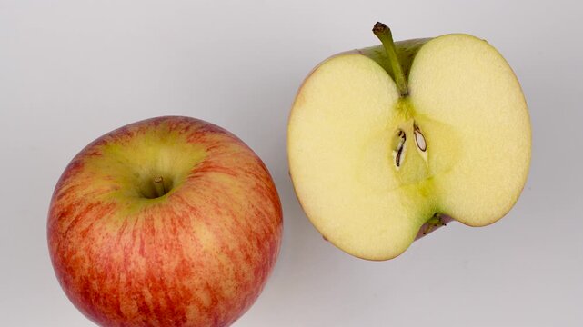 Top view of whole and half Royal Gala apples rotating. Healthy organic fruit showing skin and inside flesh isolated on white background.