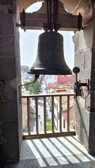 Obraz premium Large bronze church bell hanging in tower window overlooking pedestrian street of San Cristobal de La Laguna, Tenerife, Canary Islands, Spain.