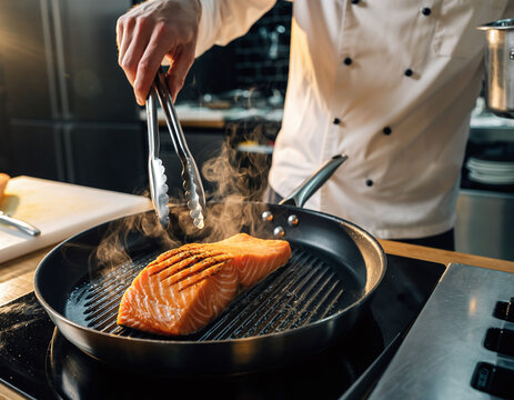 Sizzling salmon fillet cooks on a grill pan, held by a chefs tongs, showing culinary expertise, healthy eating, and delicious cuisine. Ideal for food blogs.