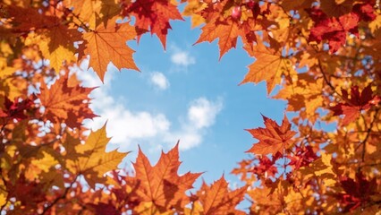 Fototapeta premium Autumn leaves surrounding a blue sky with clouds, forming a heart-shaped opening. Nature and seasonal change, fall foliage, sky view.
