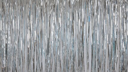 A dense arrangement of silver metallic tinsel strands with reflective and shiny qualities.