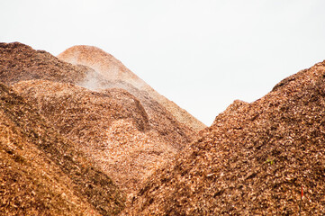 Mountains of wood chips against a gray sky close-up