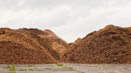 Mountains of wood chips against a gray sky close-up