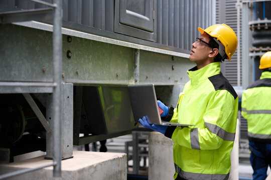 Engineers at work in a technological facility, analyzing with their laptop computer. Focused on the data, the workers are involved in technical operations and maintenance - Powered by Adobe