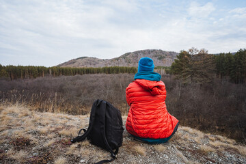 Trekker relaxes on rugged cliffside view, Backpacker taking break while admiring flowing river...