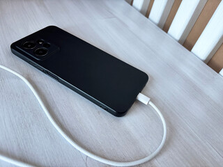 Smartphone charging with a white USB cable, mobile device connected to power adapter, home interior lifestyle, technology usage and daily digital routine concept