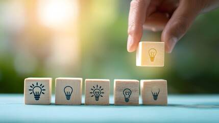 Human hand places a wooden block displaying an illuminated symbol above other blocks with illumination icons