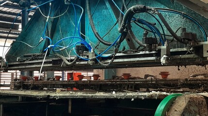 A detailed close-up of complex, grimy industrial machinery featuring bright blue pneumatic hoses and pistons.