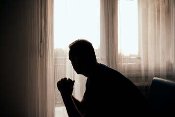 Silhouette of depressed, sad and lonely man in the apartment.