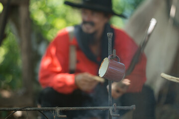 A cowboys preparing food at a campfire, roasting meat together in a warm