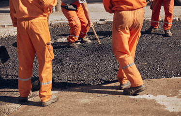 Construction worker working on a new asphalt layer on a public street.