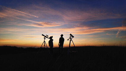 Amateur astronomer using telescope for watching stars, Moon, planets and other celestial objects from a field in nature.