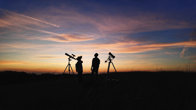 Amateur astronomer using telescope for watching stars, Moon, planets and other celestial objects from a field in nature.