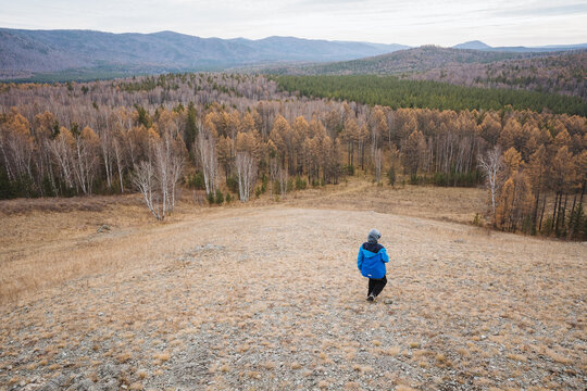 Mountain explorer on ridge trail, Traversing vast valley in autumn brightness, Solitary traveler navigates rugged terrain with contemplative mood amidst fall scenery and cloudy skies - Powered by Adobe