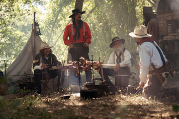 Group of cowboys preparing food at a campfire, roasting meat together in a warm