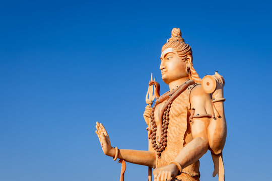 divine sculpture of lord shiva holding trident and damru with bright blue sky background