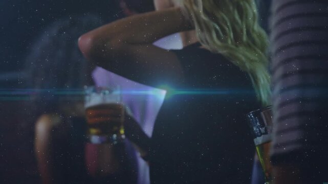 Camera pulling back revealing woman holding mug, tucking hair under lensflare, socializing bar-side