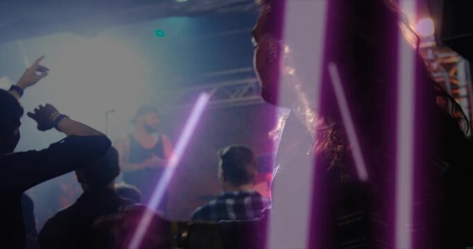 Long-haired man headbanging to music beat in concert, purple light streaks sweeping crowd