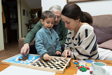Fototapeta premium Warm Family Moment: A Grandfather, Mother, and Son Joyfully Playing a Board Game Together