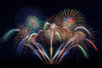 A dazzling array of colorful fireworks explodes across the night sky, featuring a symmetrical arrangement of multiple bursts in various hues.