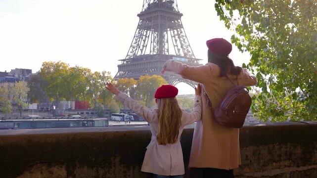 A happy tourist mother and her daughter looking at the beautiful view of the Eiffel Tower in Paris, France, during a sunny day